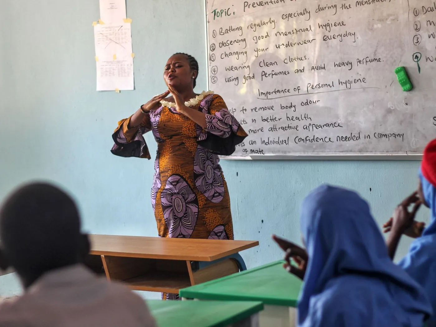 An educator presenting at a board in a classroom while participants take notes.
