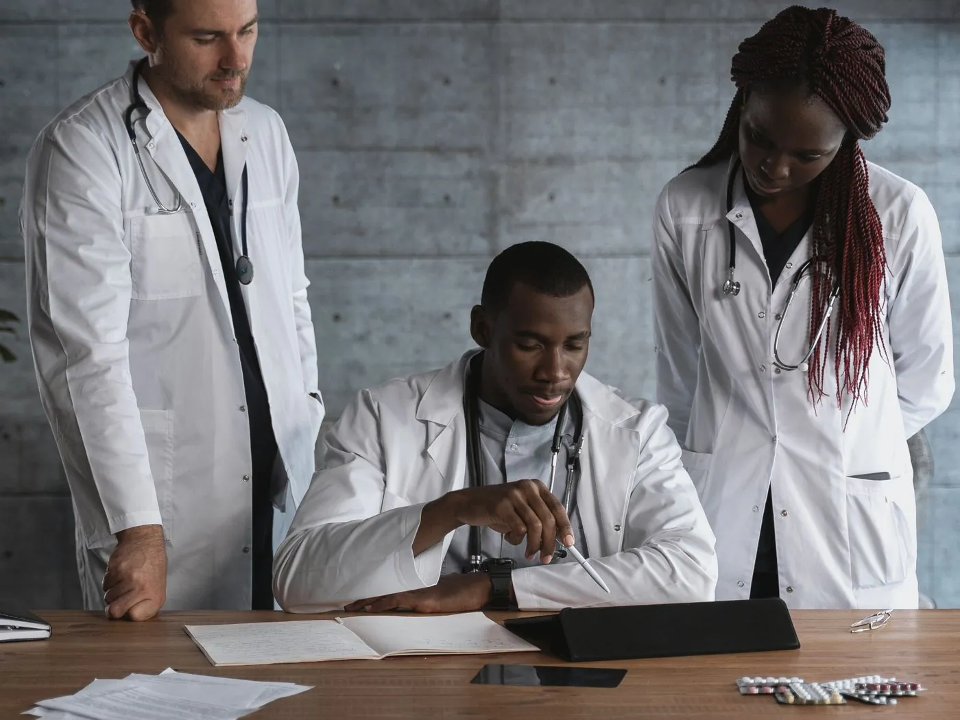 Clinicians reviewing documents together around a table in a meeting room.