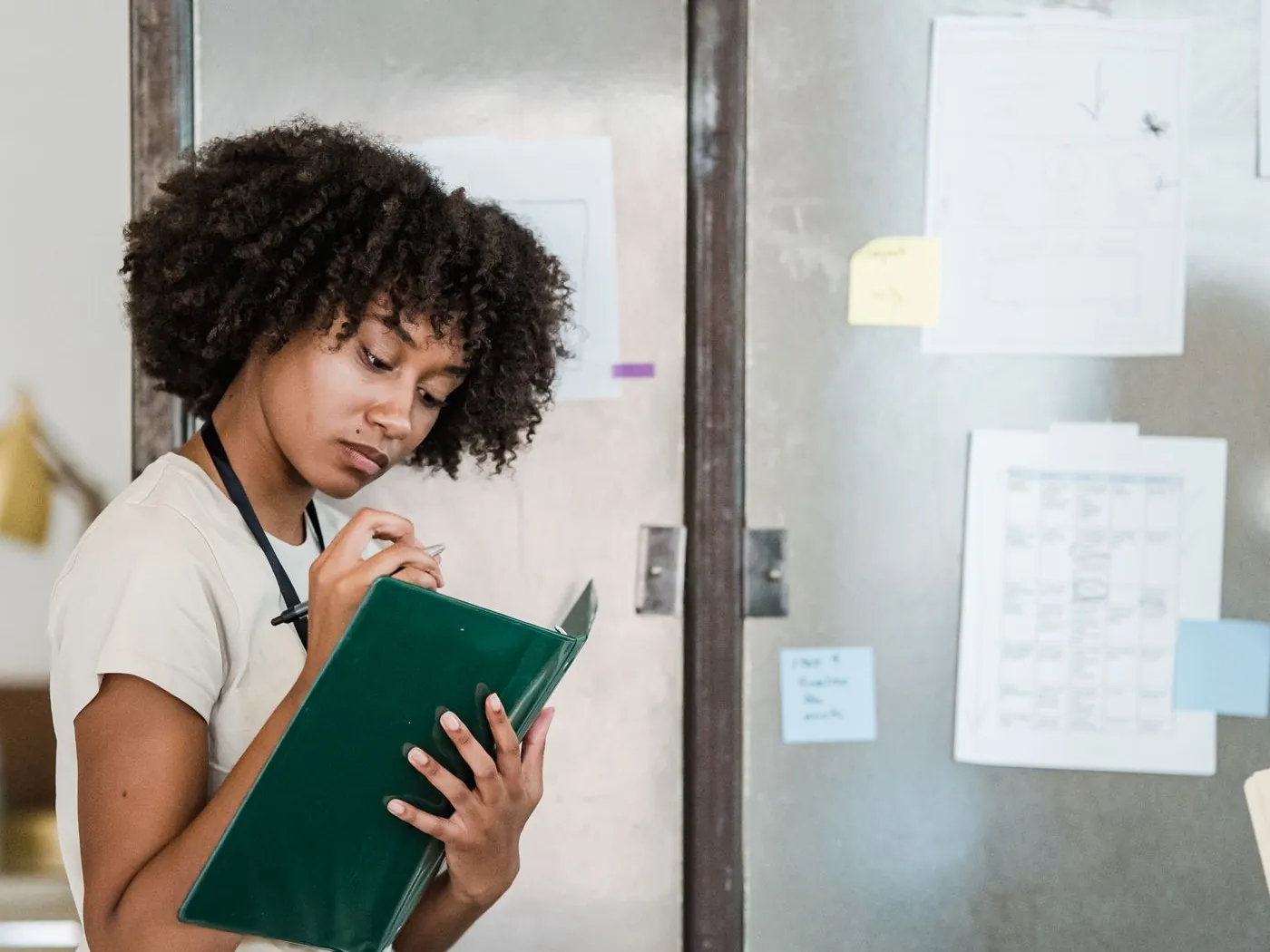 A professional reviewing notes beside a wall of process documentation.